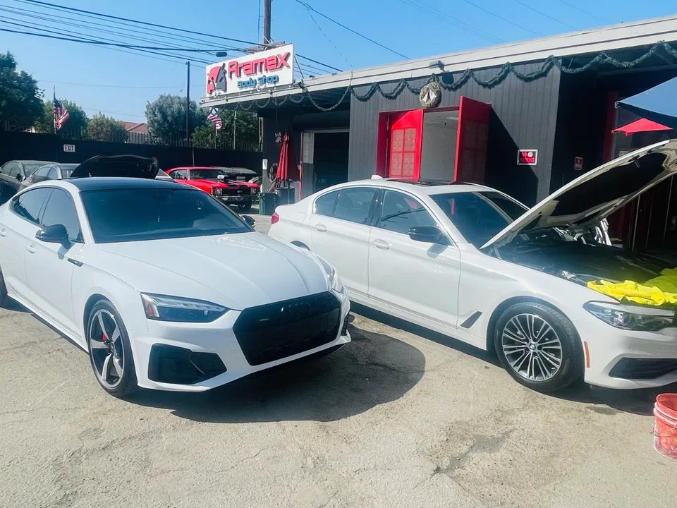 Two white Audi sedans in front of the Aramex garage