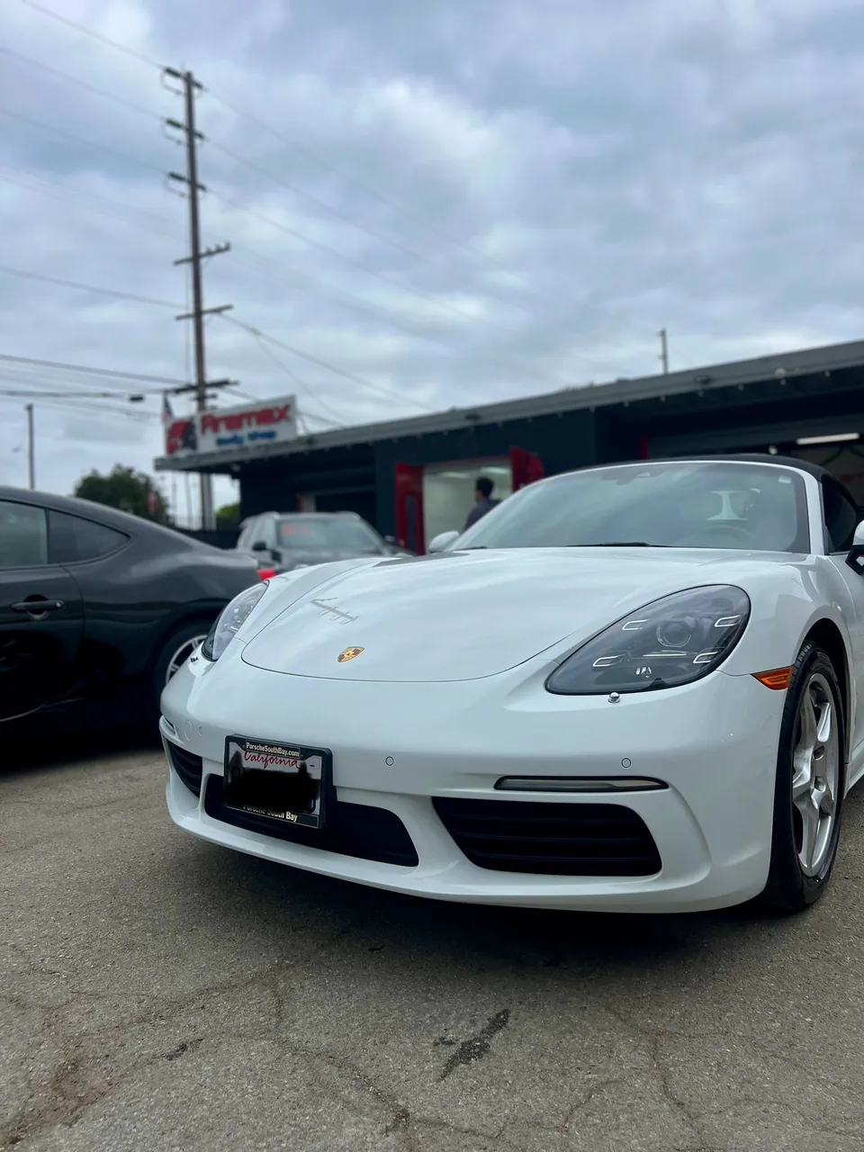 White Porsche sports car, front view, at Aramex Body Shop