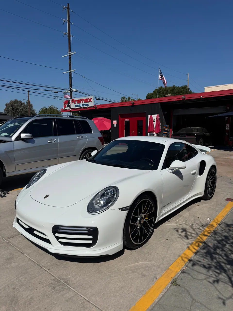 White Porsche 911 parked in front of Aramex Body Shop