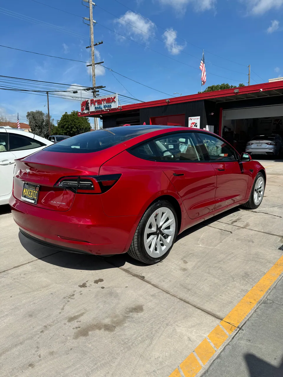 Red Tesla sedan in front of Aramex Body Shop