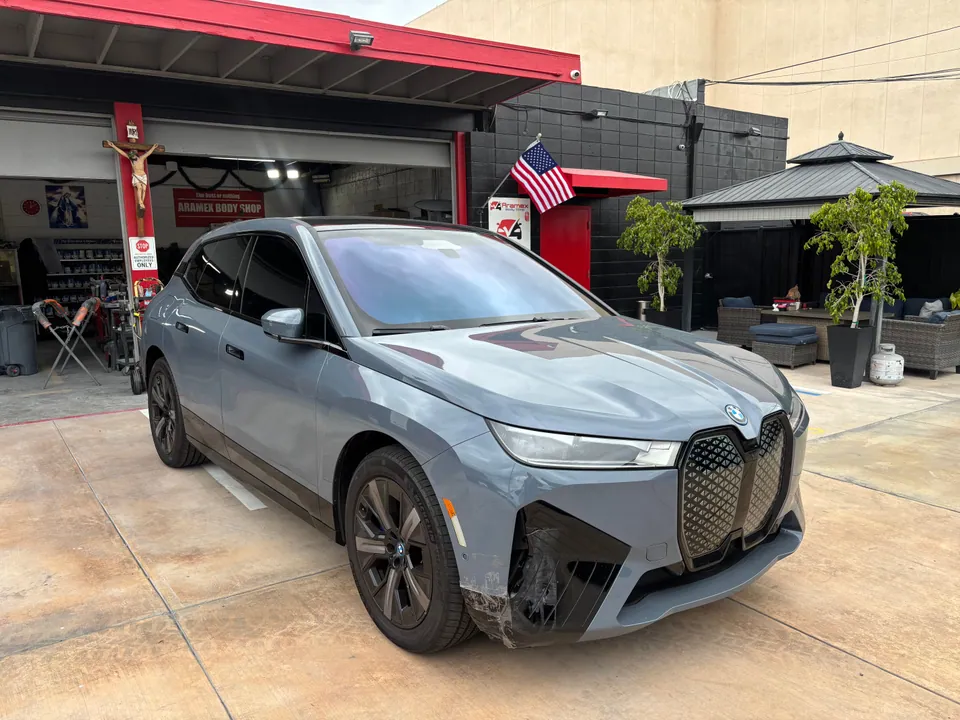 Gray BMW SUV with front-end damage outside the shop