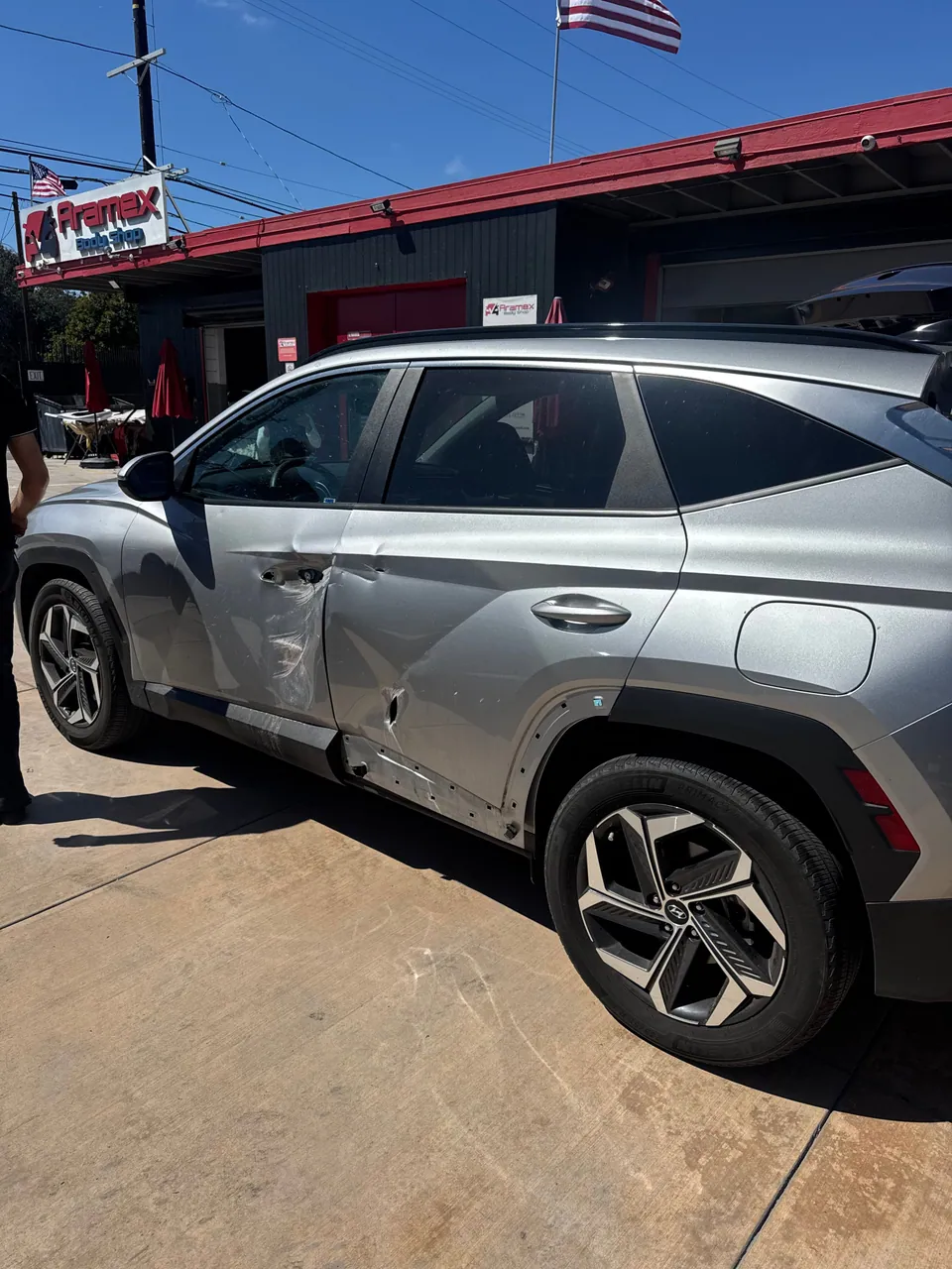 Silver Hyundai SUV with side damage waiting for repair