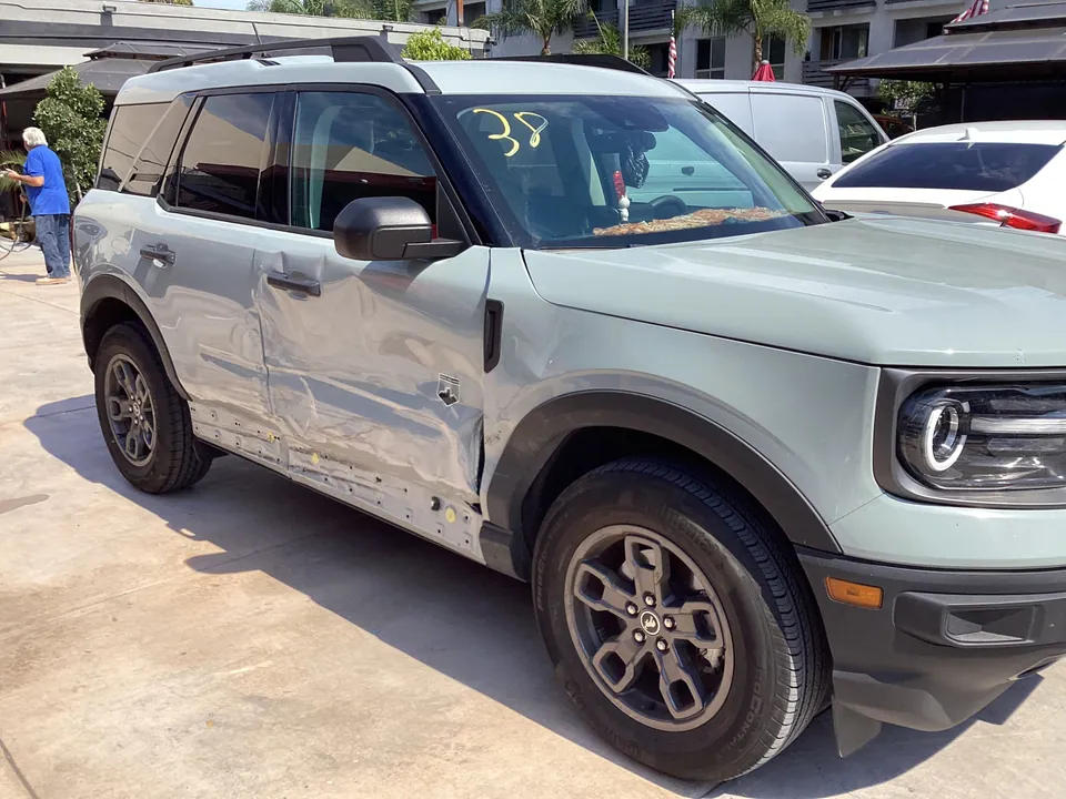 Gray Ford Bronco with side collision damage at the shop